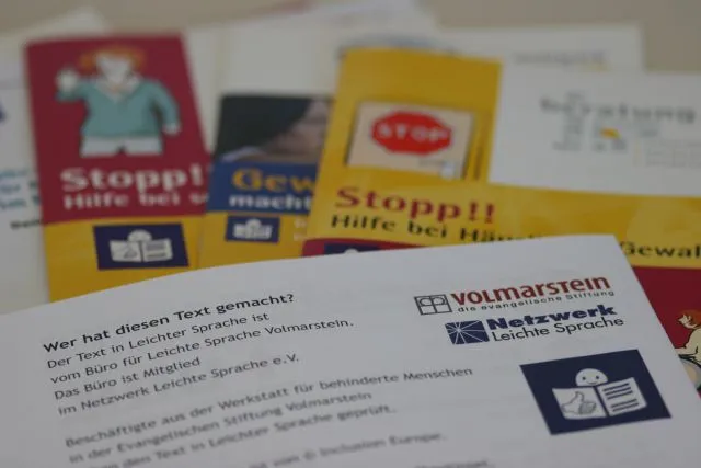 Foto von Texten und Broschüren in Leichter Sprache, mit dem Logo der Evangelischen Stiftung Volmarstein und des Netzwerks Leichte Sprache im Vordergrund.