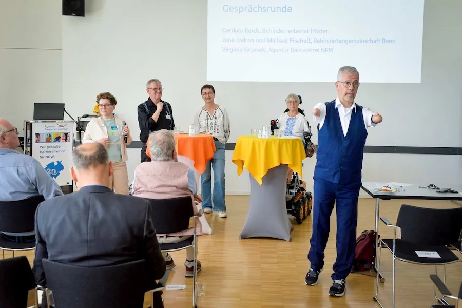 Moderator Rainer Schmidt kündigt die Podiumsdiskussion mit Virginia Grossek, Michael Fischell, Jana Jadron und Cordula Reich an