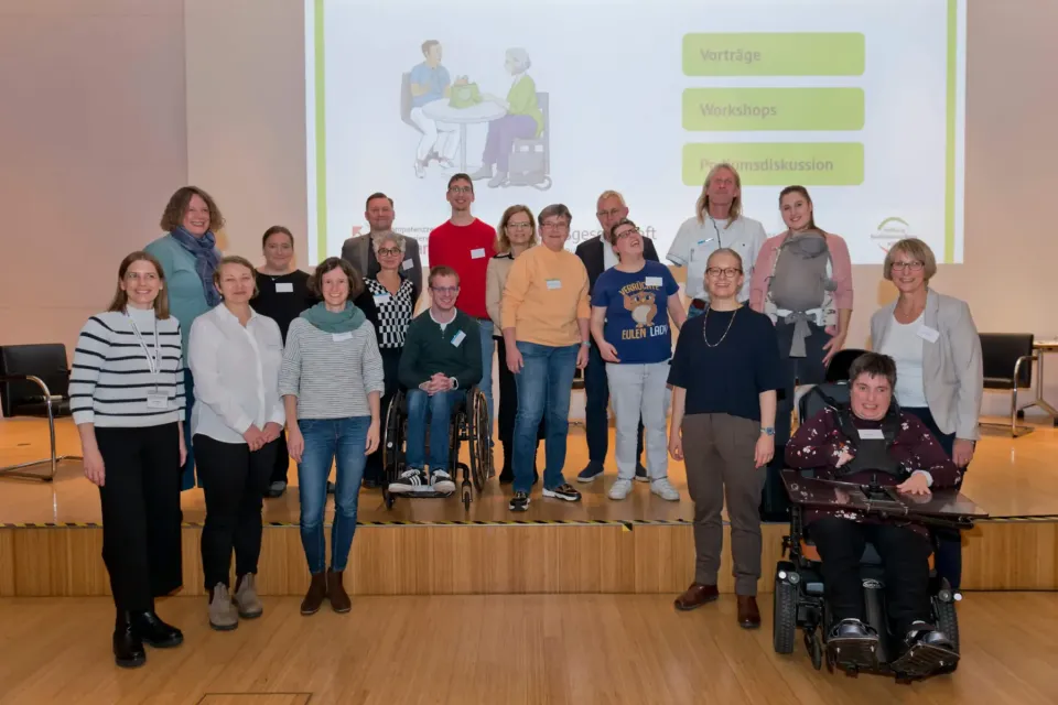 Gruppenbild von 18 Mitwirkenden des Projekts auf der Bühne des Veranstaltungsortes.