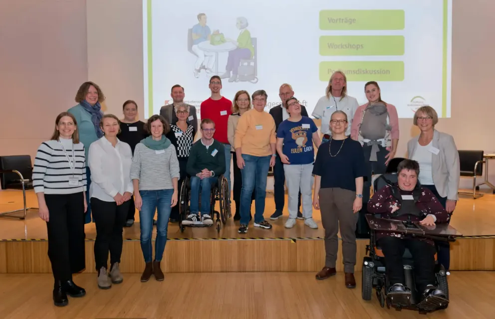 Gruppenbild von 18 Mitwirkenden des Projekts auf der Bühne des Veranstaltungsortes.