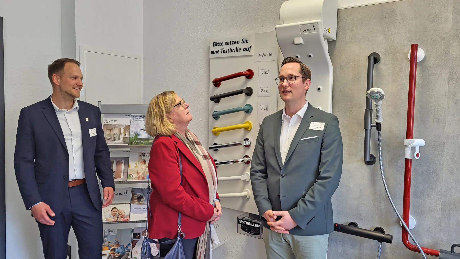 Landrat Jan-Christoph Schaberick, die stellvertretende B&uuml;rgermeisterin und MdL Kirsten Stich und Joel Stieglitz vom Ennepe-Ruhr-Kreis probieren den K&ouml;rperf&ouml;hn aus, der nach dem Duschen Menschen mit Behinderung hilft, sich zu trocknen.