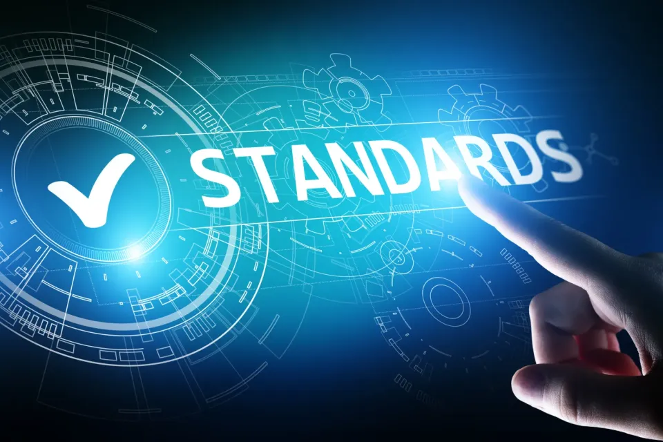 Eine Person bedient eine futuristische Oberfläche aus verknüpften Zahnrädern, in deren Zentrum der Text Standards steht.