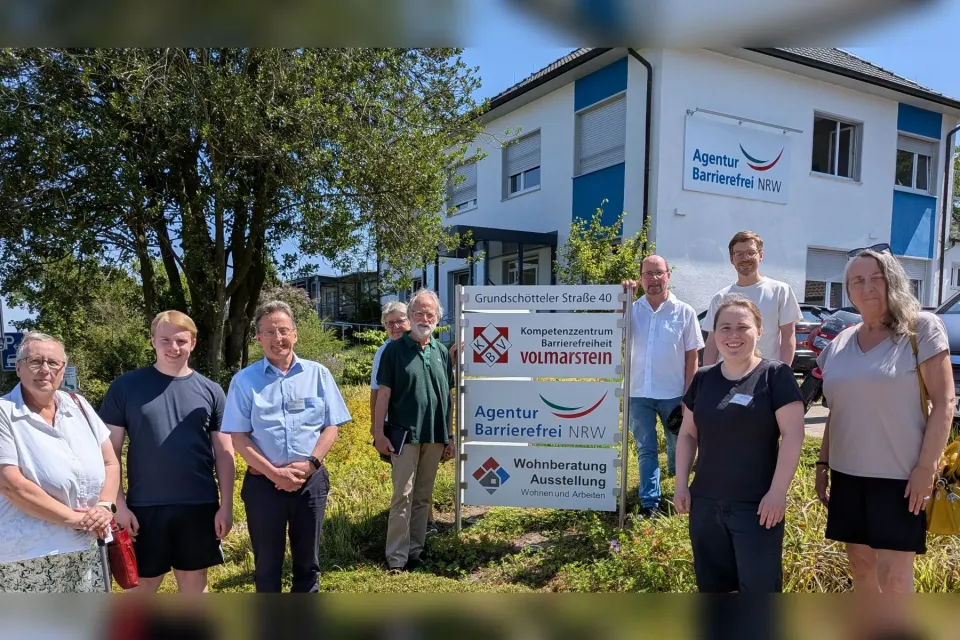 Foto der Besuchergruppe mit 7 Personen und den beiden Wohnberatern am Eingangsschild des KBV. Im Hintergrund das Gebäude.