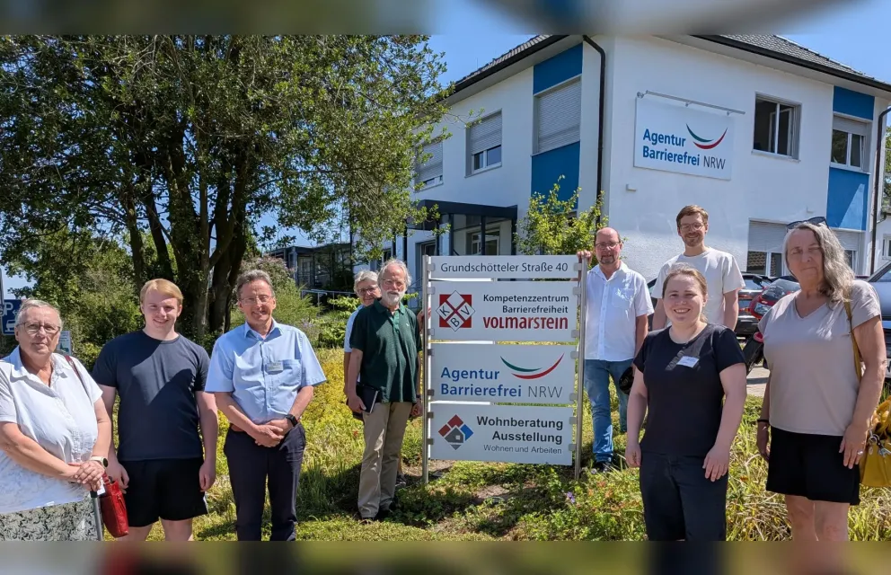 Foto der Besuchergruppe mit 7 Personen und den beiden Wohnberatern am Eingangsschild des KBV. Im Hintergrund das Gebäude.