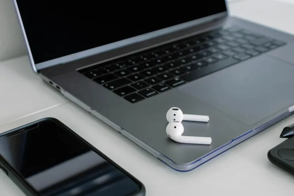 Foto von auf einem Notebook liegenden In-Ear-Kopfhörern