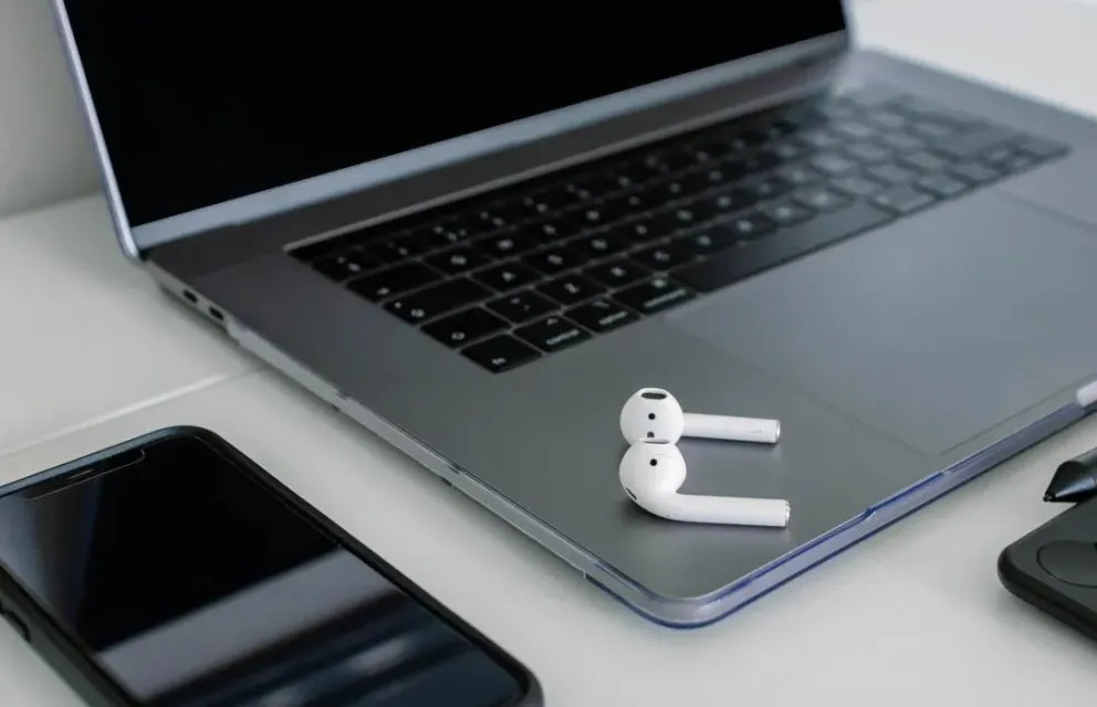 Foto von auf einem Notebook liegenden In-Ear-Kopfhörern