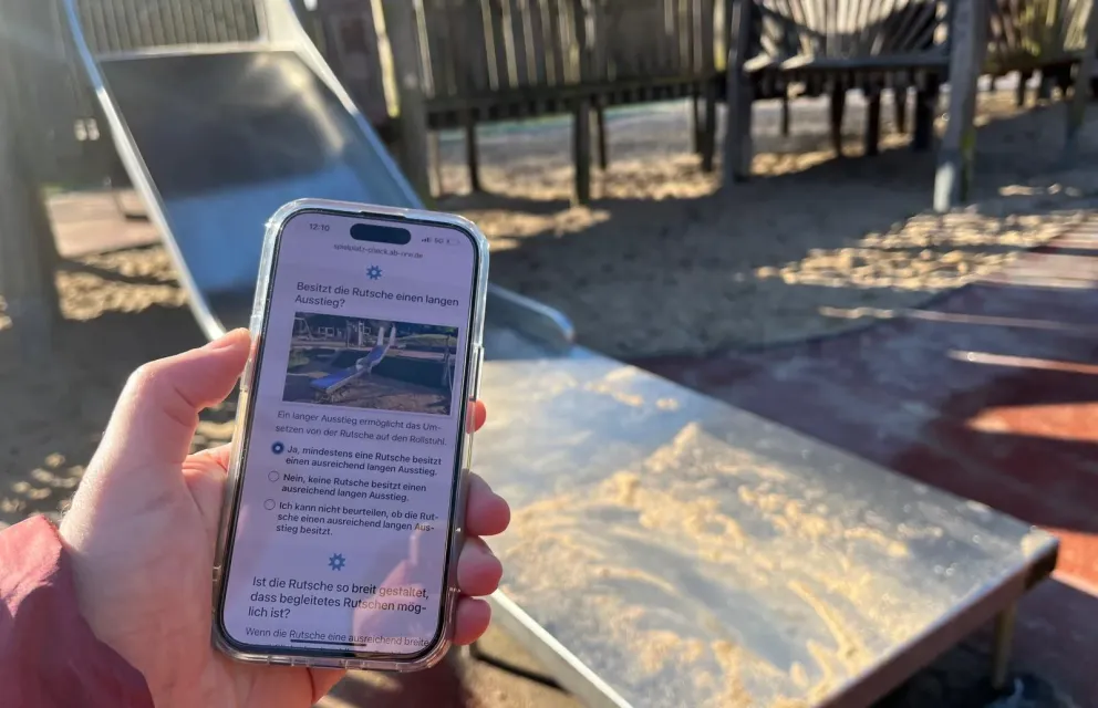 App Spielplatz-Check im Einsatz auf einem Smartphone an einer Rutsche mit langem Ausstieg auf einem Spielplatz