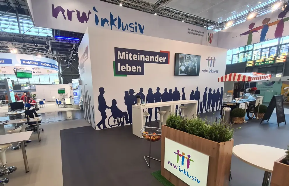Foto des noch leeren Messestands der Landesregierung NRW mit dem Schriftzug nrw inklusiv, Miteinander leben.