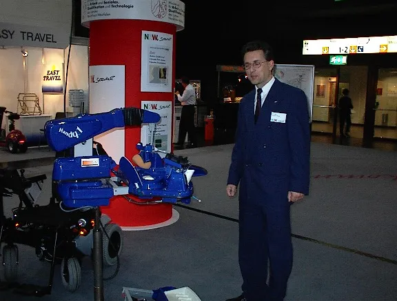 Dr. Helmut Heck neben dem Exponat Handy1 auf der Rehacare.