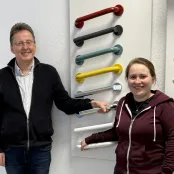 Foto von den Wohnberatern Hans-Werner Geburek und Hanja Laumann vor einer Wand mit verschiedenfarbigen Haltegriffen